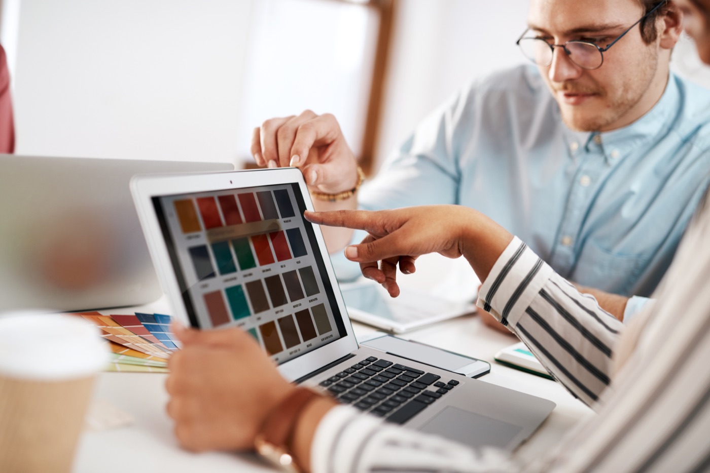 People reviewing color palettes on a laptop during a website design discussion.