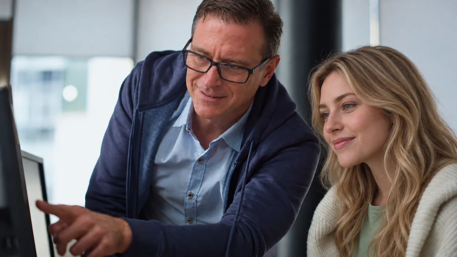 Perry Gordon pointing to a computer screen while a woman reviews it beside him.